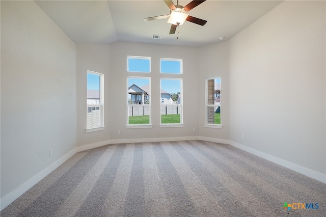 carpeted spare room featuring vaulted ceiling and ceiling fan