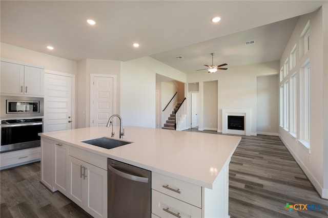 kitchen featuring stainless steel appliances, white cabinetry, sink, dark hardwood / wood-style floors, and an island with sink