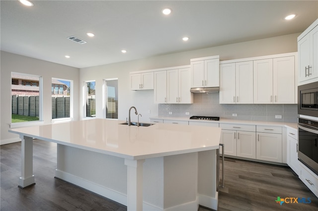 kitchen featuring appliances with stainless steel finishes, sink, an island with sink, and dark hardwood / wood-style floors