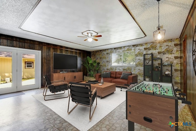 living room with a textured ceiling, wood walls, and ceiling fan