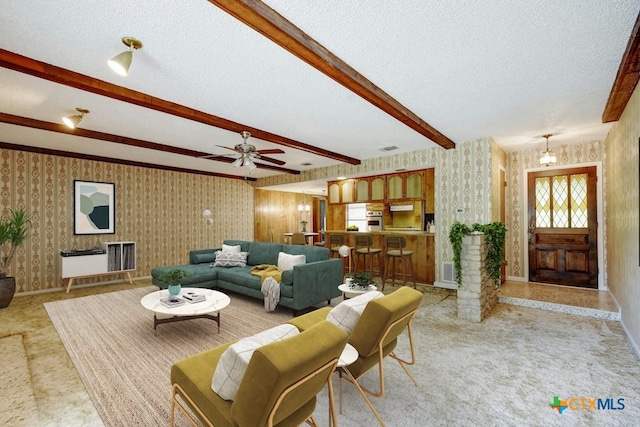 living room with light carpet, ceiling fan, beam ceiling, a textured ceiling, and ornate columns