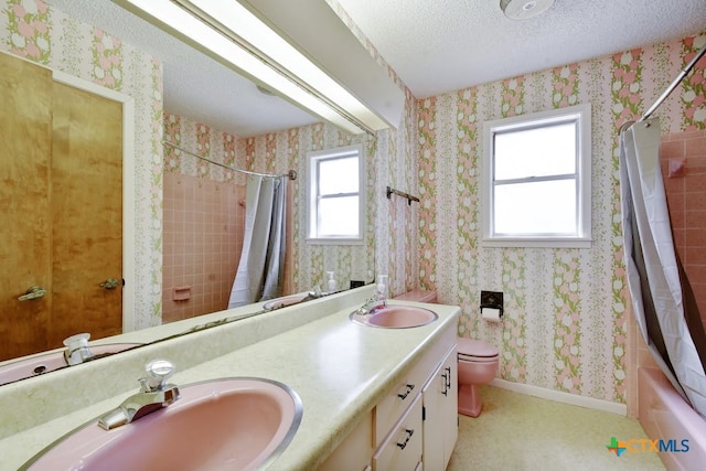 full bathroom with shower / tub combo with curtain, vanity, toilet, and a textured ceiling