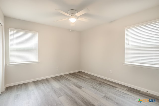 unfurnished room featuring a wealth of natural light, ceiling fan, and light wood-type flooring