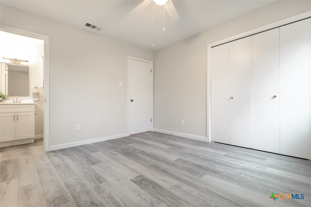 unfurnished bedroom with ceiling fan, a closet, light wood-type flooring, and ensuite bath