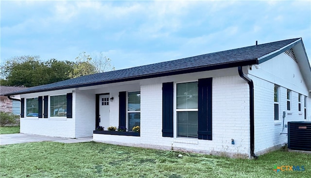 ranch-style house featuring a front lawn and central AC unit