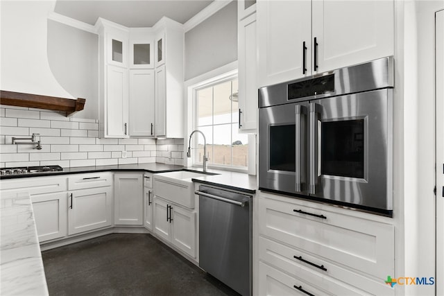 kitchen featuring appliances with stainless steel finishes, white cabinets, dark stone counters, and decorative backsplash