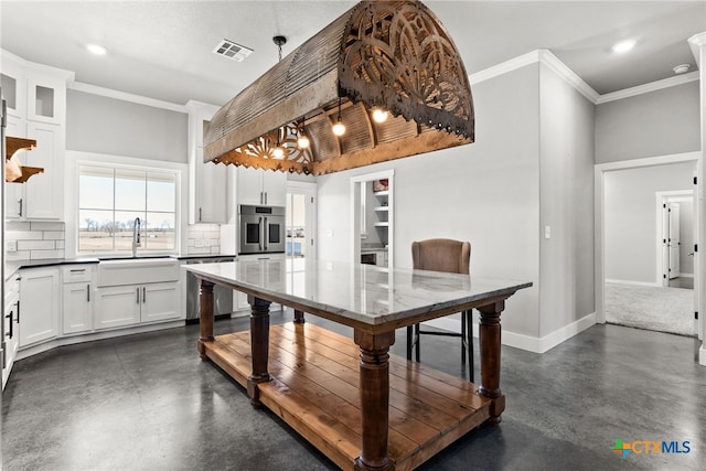 kitchen featuring pendant lighting, sink, backsplash, stainless steel appliances, and white cabinets