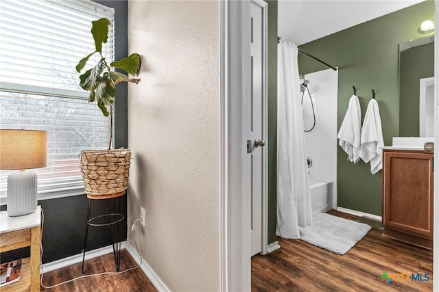 bathroom with plenty of natural light, shower / bath combination with curtain, and hardwood / wood-style flooring