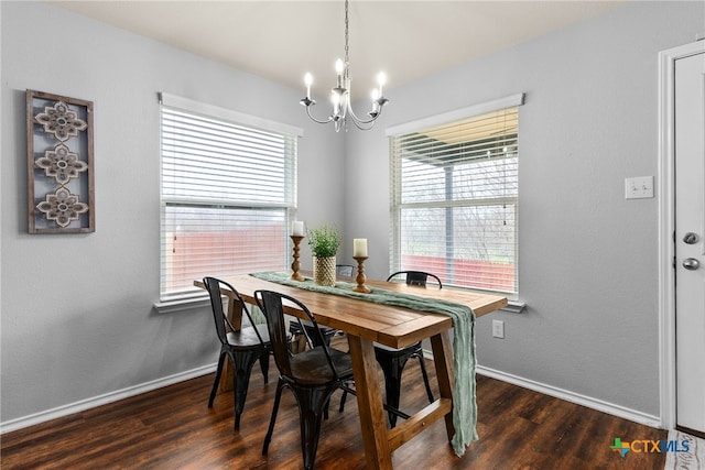 dining room with dark wood-type flooring and an inviting chandelier