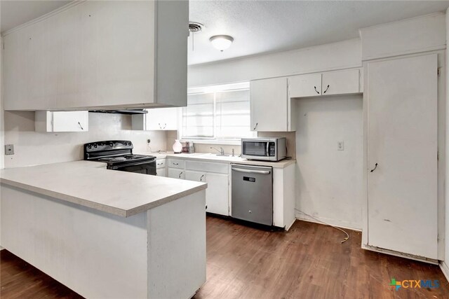 2307 E Airline Rd, Victoria, TX 77901 - kitchen with appliances with stainless steel finishes, a peninsula, light countertops, white cabinetry, and dark wood finished floors