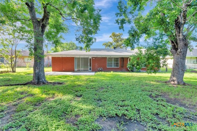 2307 E Airline Rd, Victoria, TX 77901 - rear view of house featuring a lawn, brick siding, and a patio area