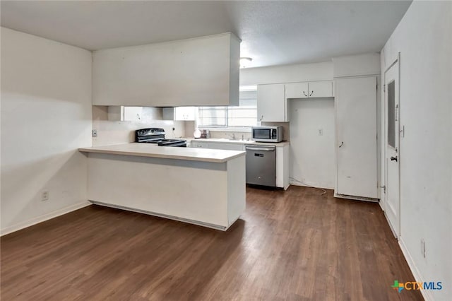 2307 E Airline Rd, Victoria, TX 77901 - kitchen featuring stainless steel appliances, a peninsula, dark wood-type flooring, white cabinets, and light countertops