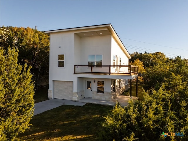 back of house featuring a garage, a balcony, and a yard