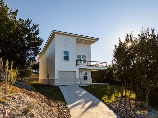 modern home with a balcony, a front yard, and a garage