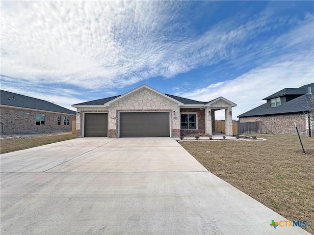 view of front of house featuring a garage, brick siding, fence, concrete driveway, and a front lawn