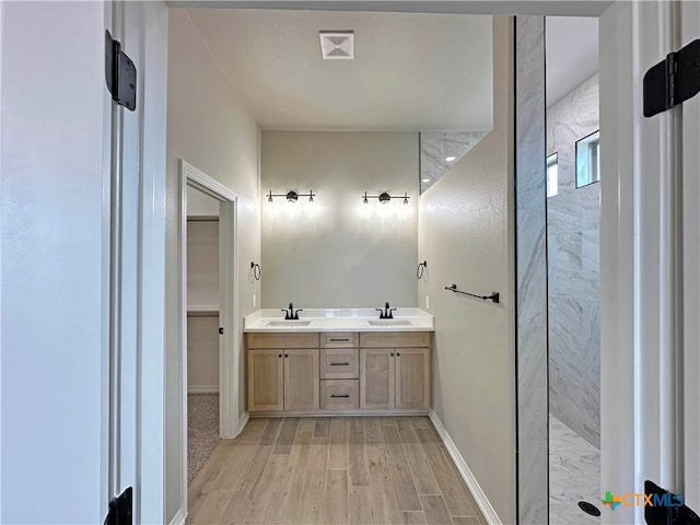 full bathroom featuring a walk in shower, visible vents, a sink, and wood finished floors