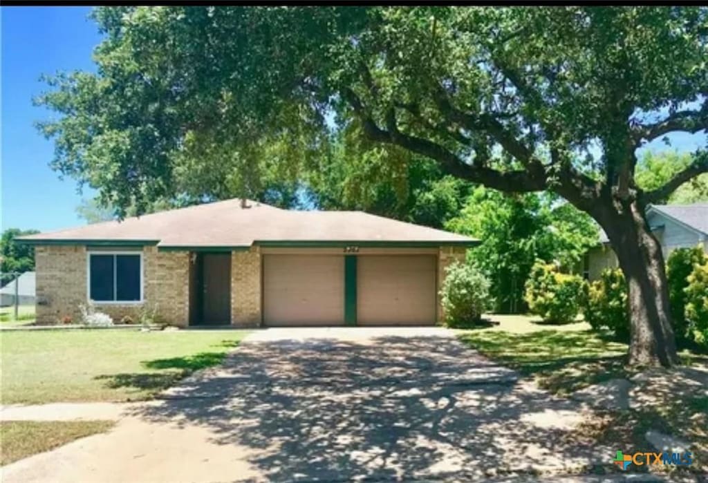 ranch-style house with a front lawn, an attached garage, and driveway