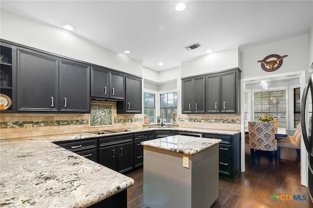 504 Masters Dr, Victoria, TX 77904 - kitchen featuring dark wood-style flooring, light stone counters, tasteful backsplash, a kitchen island, and recessed lighting