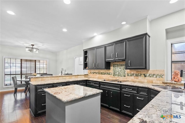 504 Masters Dr, Victoria, TX 77904 - kitchen featuring a peninsula, black electric stovetop, tasteful backsplash, dark cabinetry, and light stone countertops