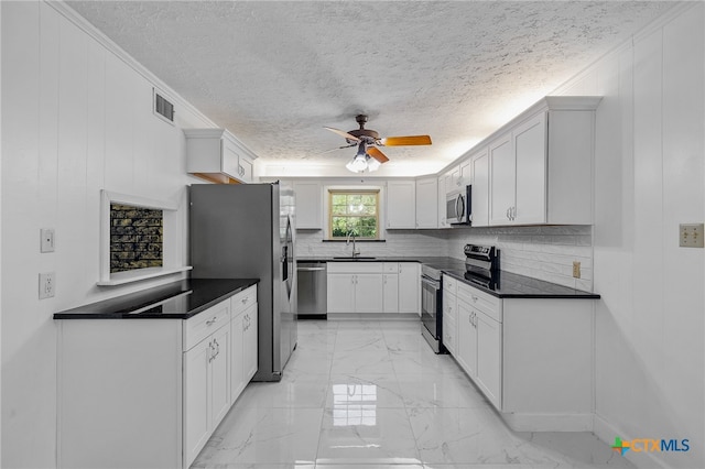 kitchen featuring backsplash, white cabinetry, stainless steel appliances, and a textured ceiling