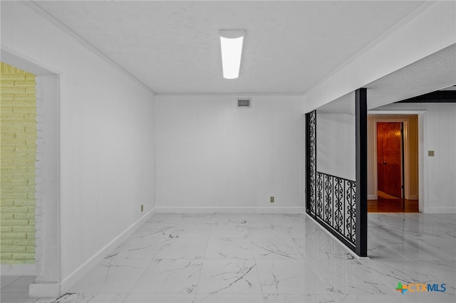 spare room featuring ornamental molding, a textured ceiling, and wooden walls