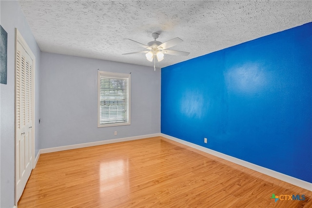 unfurnished bedroom with ceiling fan, light wood-type flooring, a textured ceiling, and a closet