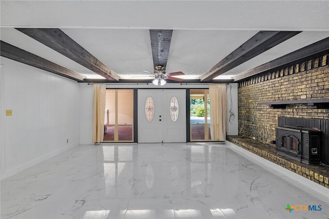 unfurnished living room with a wood stove, ceiling fan, and beamed ceiling