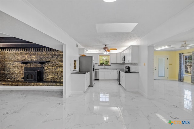 unfurnished living room with a skylight, a wood stove, plenty of natural light, and sink