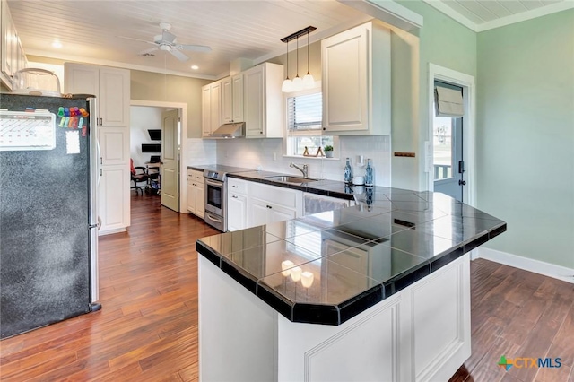 11 Enchanted Ln, Port Lavaca, TX 77979 - kitchen with stainless steel appliances, a peninsula, ornamental molding, dark wood-style floors, and tasteful backsplash