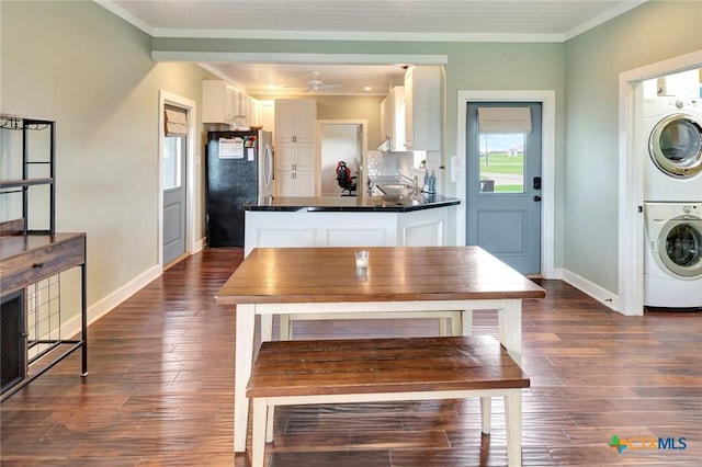 11 Enchanted Ln, Port Lavaca, TX 77979 - kitchen with stacked washer / dryer, freestanding refrigerator, white cabinetry, dark wood-style floors, and crown molding