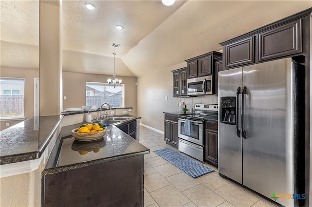 kitchen with stainless steel appliances, lofted ceiling, a notable chandelier, sink, and pendant lighting