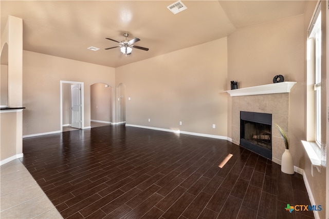 unfurnished living room featuring dark wood-type flooring, ceiling fan, lofted ceiling, and a tile fireplace