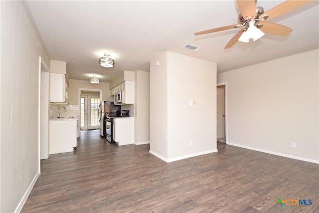 unfurnished living room featuring wood walls, dark hardwood / wood-style floors, ceiling fan, and sink