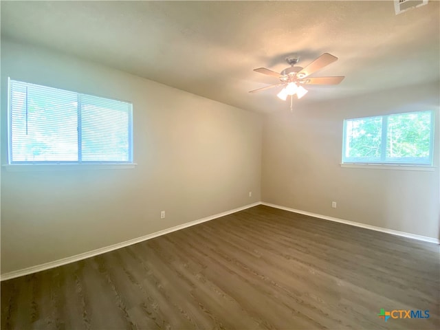 unfurnished room featuring a wealth of natural light, ceiling fan, and dark hardwood / wood-style flooring