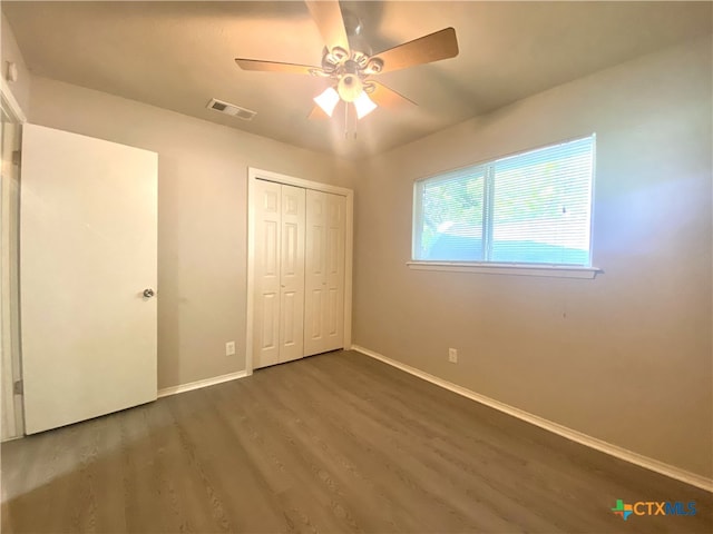 unfurnished bedroom with ceiling fan, dark hardwood / wood-style floors, and a closet