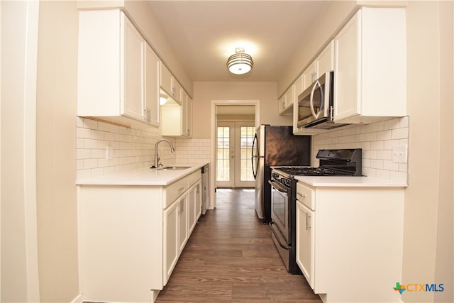 kitchen featuring white cabinetry, appliances with stainless steel finishes, dark hardwood / wood-style floors, decorative backsplash, and sink