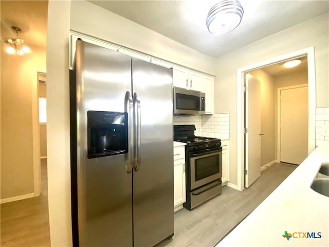 kitchen featuring white cabinetry, appliances with stainless steel finishes, backsplash, light wood-type flooring, and sink