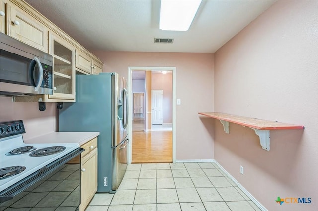 4803 Chad Dr, Killeen, TX 76542 - kitchen with light countertops, range with electric cooktop, stainless steel microwave, visible vents, and glass insert cabinets