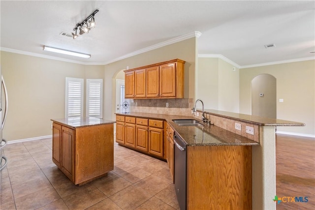 127 Ariana Ct, Killeen, TX 76542 - kitchen featuring arched walkways, dishwasher, a kitchen island, dark stone counters, and ornamental molding
