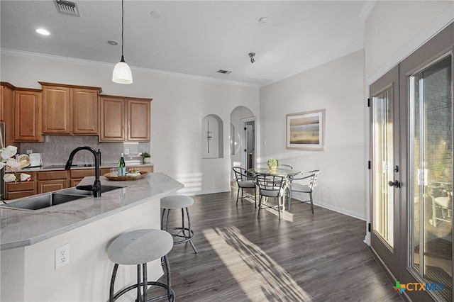 kitchen featuring light stone countertops, tasteful backsplash, crown molding, and sink