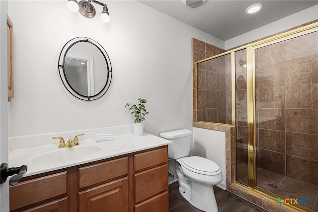 bathroom featuring wood-type flooring, vanity, toilet, and a shower with door