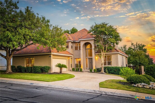 mediterranean / spanish home with a yard and a garage