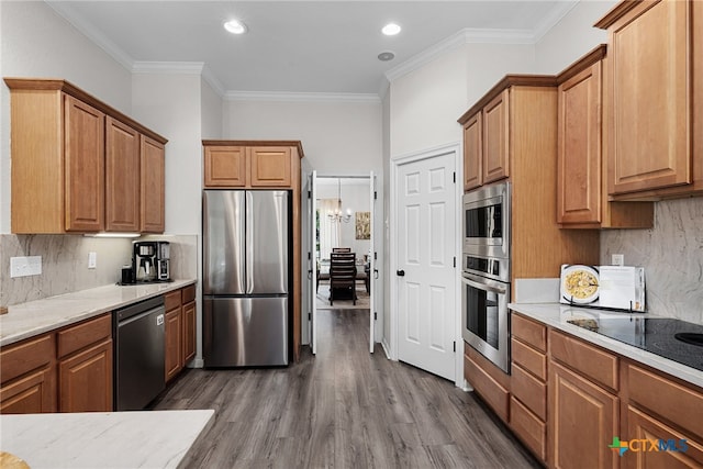 kitchen with ornamental molding, stainless steel appliances, dark wood-type flooring, and an inviting chandelier