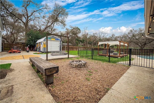 view of yard featuring an outbuilding, a shed, an outdoor fire pit, and fence