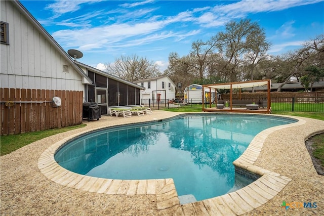 view of swimming pool with an outbuilding, a fenced backyard, a storage shed, a sunroom, and a fenced in pool