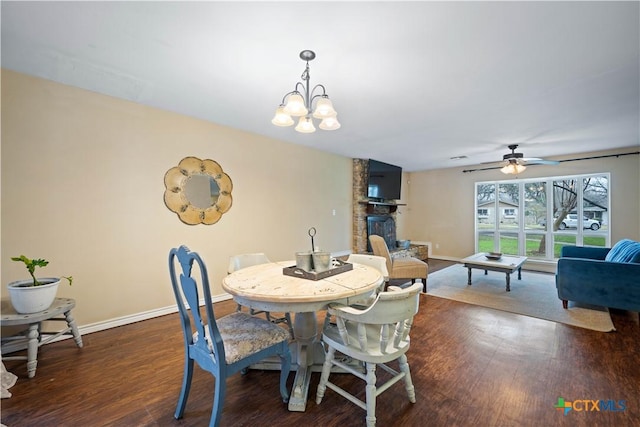 dining area with a fireplace, baseboards, dark wood-type flooring, and ceiling fan with notable chandelier