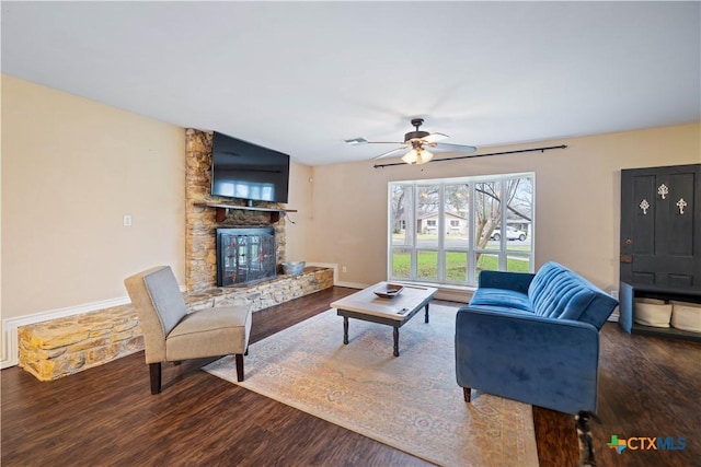 living area featuring baseboards, visible vents, wood finished floors, and a stone fireplace