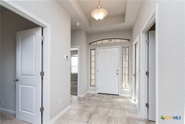 entrance foyer featuring a raised ceiling and light carpet