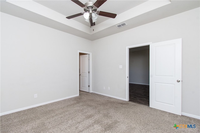 unfurnished bedroom with a tray ceiling, ceiling fan, and carpet