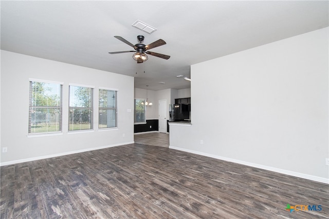 unfurnished living room featuring ceiling fan with notable chandelier and dark wood-type flooring